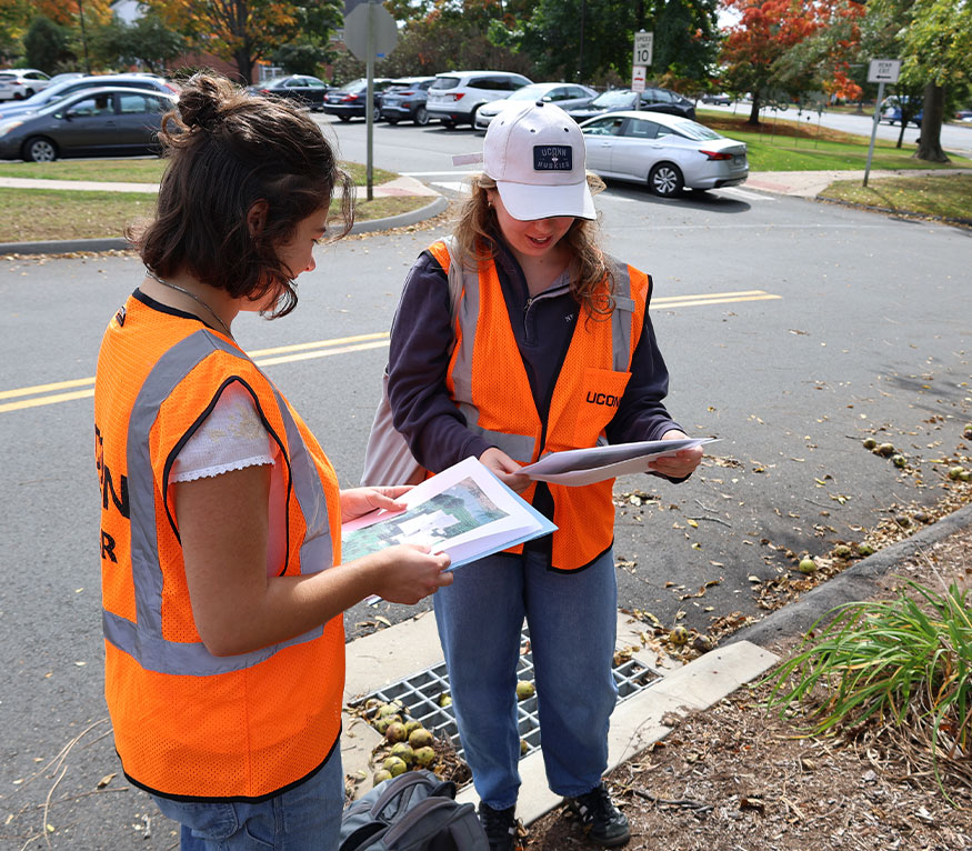 students reviewing notes near a storm drain